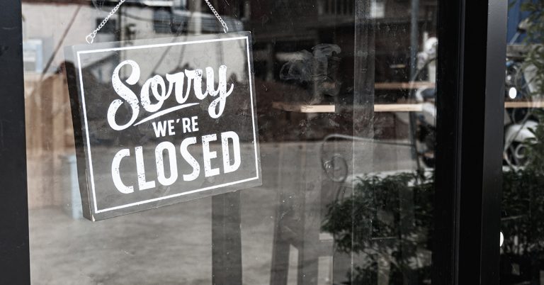 A retail store main door with a Sorry we Are Closed sign