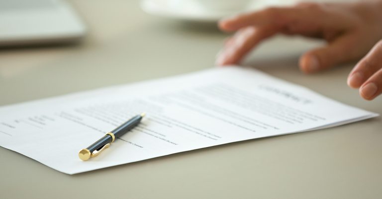 Hands handing over a document to sign with a pen on top of the paper