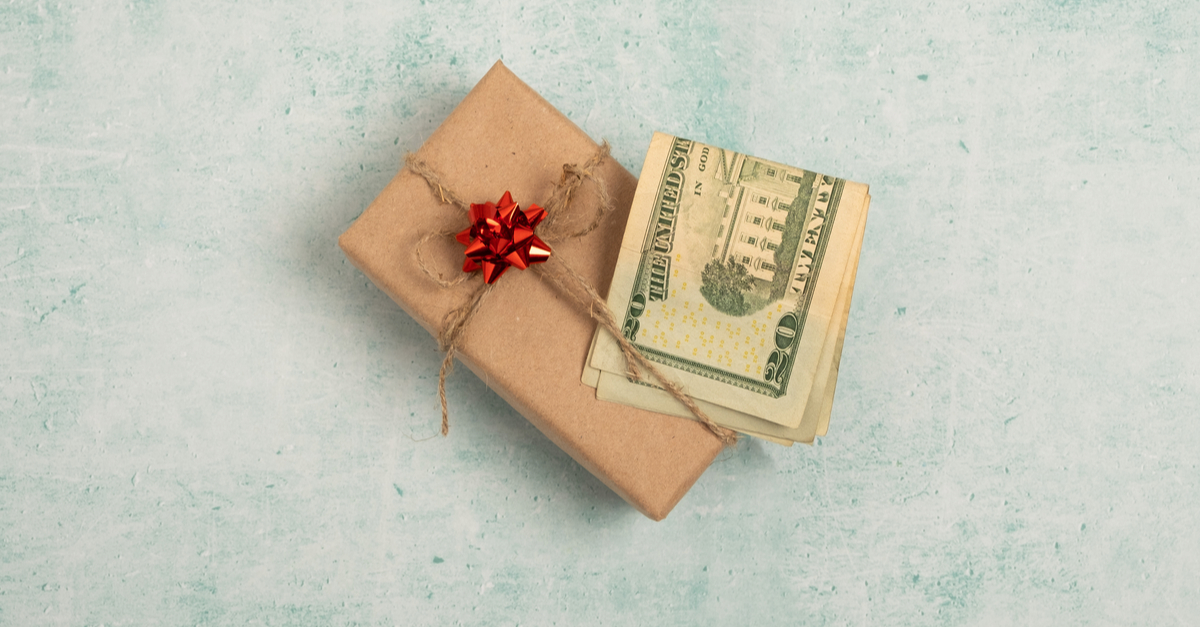 Photo of folded 20 dollar bills stuffed under ribbon holding a gift together.